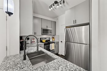 A kitchen with a stainless steel refrigerator and a sink with a black faucet.